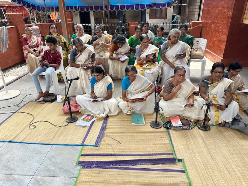 Cultural event with devotees seated inside the temple hall.