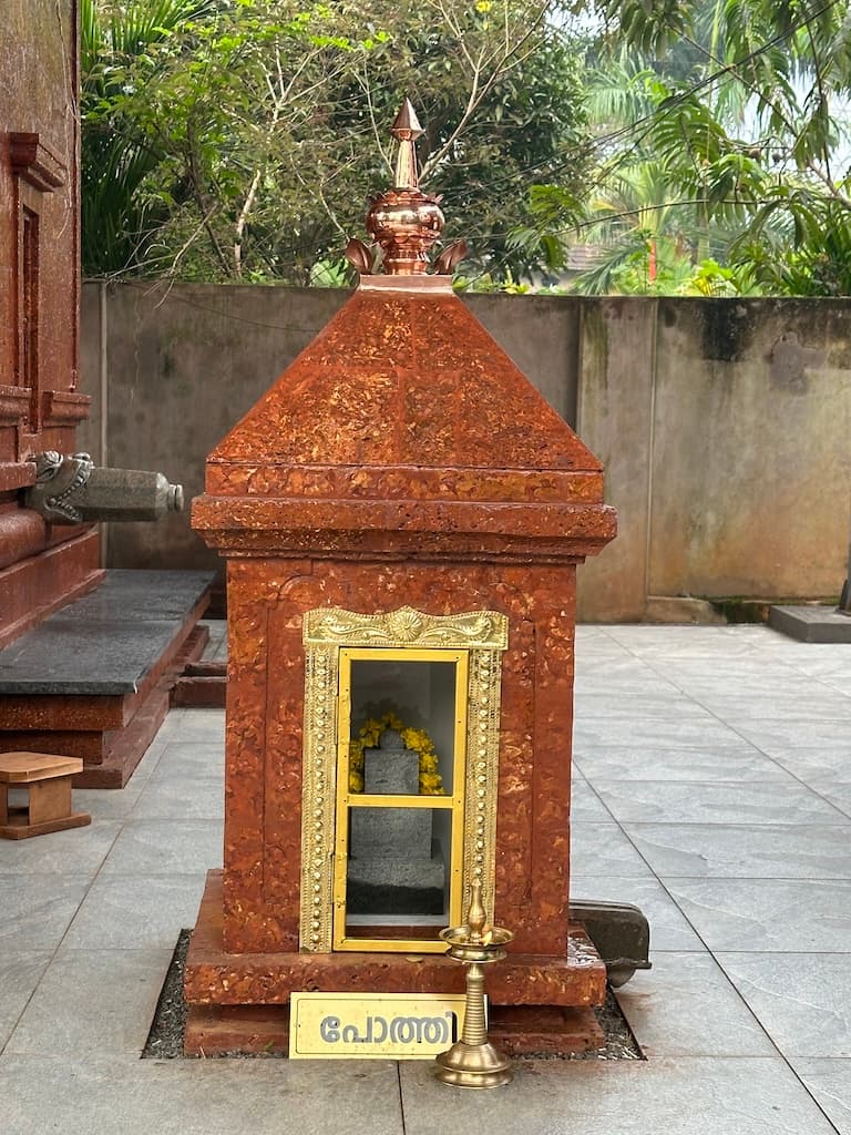 Deity statue with floral garlands inside the shrine.